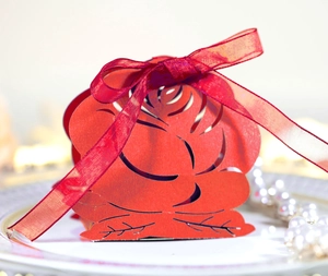 Laser-cut red rose wedding favor box with silk ribbon bow on white jewelry tray