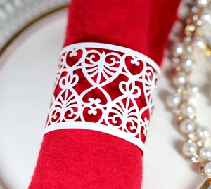 Macro detail of laser-cut white heart napkin rings on red fabric for wedding decor