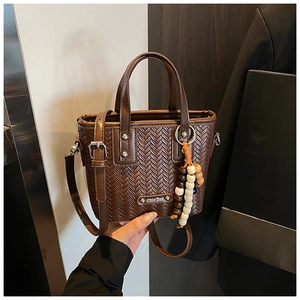 Détail du sac à texture tissée marron avec breloque en perles et anses en cuir