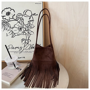 Close-up of a dark brown suede bucket bag featuring long fringe tassels and thin double straps