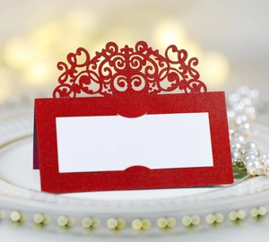 Détail du marque-place rouge découpé au laser avec motif dentelle sur une assiette