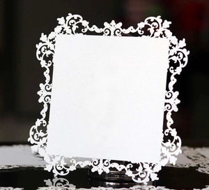 Close-up of white laser-cut card with intricate floral lace patterns for decoration