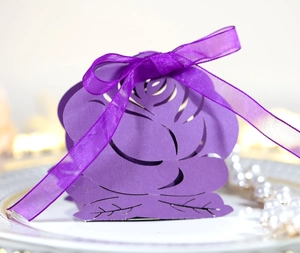 Purple laser cut rose favor box with ribbon bow on an elegant white jewelry tray