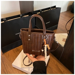 Détail du sac cabas tressé marron foncé avec pendentif en perles et bandoulière réglable