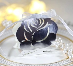 Detail of laser-cut rose candy box in silver metallic cardstock with a white silk bow