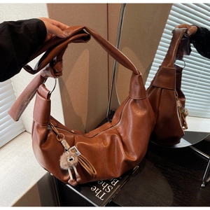 Detail of caramel brown PU leather hobo bag with knotted strap and cute tassel charm