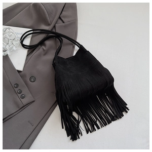 Close-up of black suede bucket bag featuring long fringe tassels and a slim shoulder strap