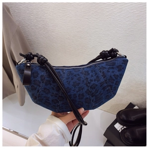 Dettaglio borsa croissant in denim leopardato con tracolla in pelle annodata