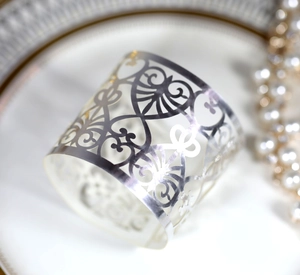 Detail view of silver laser-cut hollow pattern napkin ring on a decorative plate
