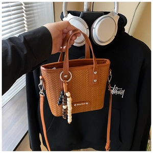 Détail du sac seau marron tissé avec breloque en perles et bandoulière réglable