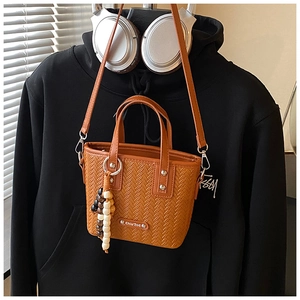 Détail du sac tressé avec perles en bois et logo métallique sur fond style de vie chic