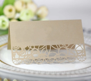 Close-up of champagne gold laser-cut table card with hollow lace detail on a ceramic plate