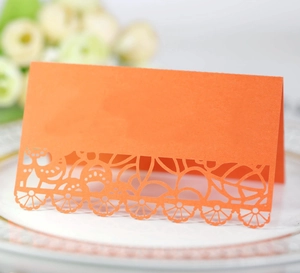 Elegant orange place card with laser-cut lace floral pattern for wedding table setting