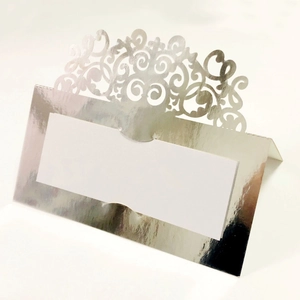 Elegant silver laser-cut wedding place card with intricate lace scrollwork and white insert