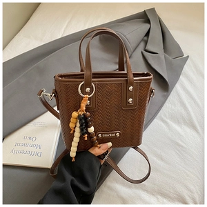 Détail du sac cabas tressé marron foncé avec pompon en perles de bois multicolores
