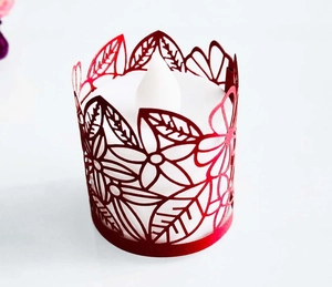 Top view of laser-cut red paper candle wrap with detailed floral and leaf hollow patterns