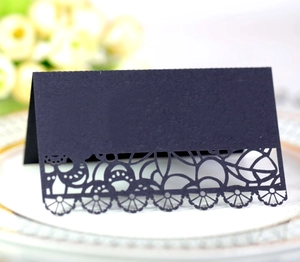 Elegant navy laser-cut lace wedding place card on a white dinner plate with gold trim