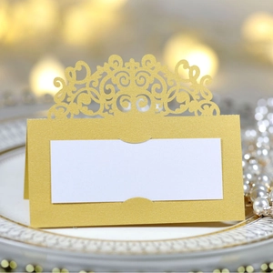 Elegant gold laser-cut lace place card for weddings and events on a white ceramic plate