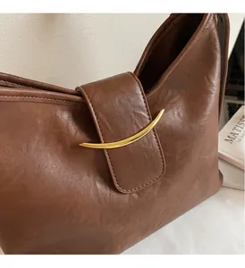 Detail of premium brown leather tote with signature golden crescent hardware