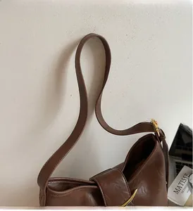 Detailed close-up of dark brown leather shoulder bag with vintage gold metal buckle