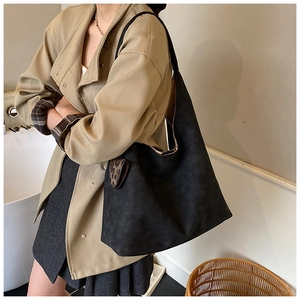 Detail view of large black suede tote bag with leopard print accent on shoulder