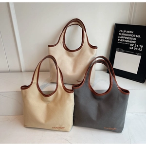 Three minimalist canvas tote bags in cream, khaki, and grey with leather trim details