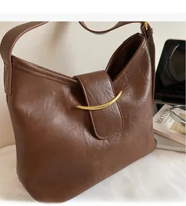 Detailed close-up of dark brown leather crossbody bag with crescent gold metal buckle