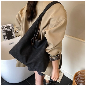 Minimalist black matte hobo bag with large capacity shown over a khaki coat