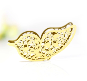 Detail of laser-cut gold butterfly paper craft with hollow floral pattern and reflection