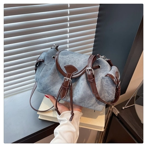 Dettaglio della borsa a tracolla in denim blu con finiture in pelle marrone e coulisse