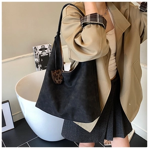 Detail of black hobo tote bag featuring a textured finish and leopard heart charm