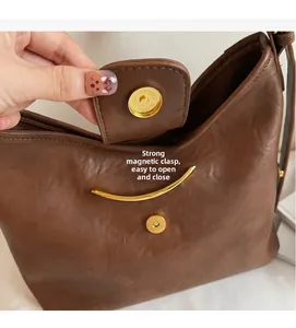 Detail view of the deep brown leather tote featuring a golden magnetic snap closure