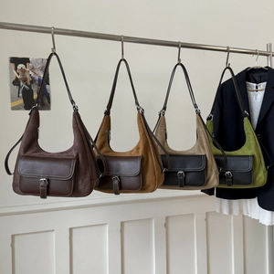 Detail of four retro suede hobo bags in assorted colors hanging on metal hangers