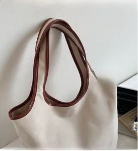 Detail of reinforced leather handle and stitching on large capacity off-white canvas tote bag