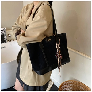 Dettaglio della borsa tote in tela nera con finiture in pelle e nappine decorative