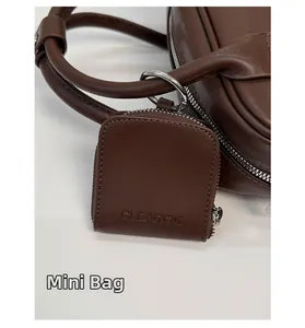 Detail of a dark brown mini leather pouch with a zipper and metal hook attachment