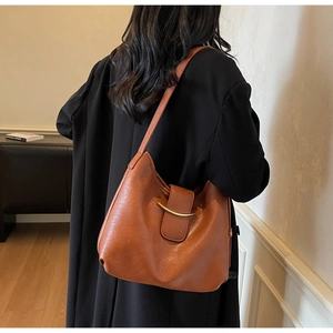 Detail of a brown leather tote bag showing the elegant golden curved metal closure design