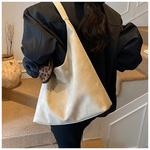 Creamy hobo tote bag with a leopard heart charm shown on model in an indoor setting