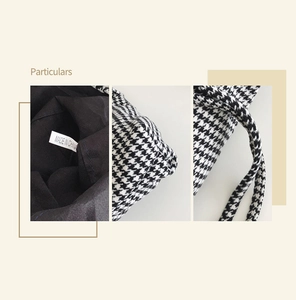 Detail view of houndstooth fabric texture, black lining, and handle stitching on tote bag