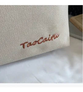 Detail of minimalist beige canvas tote bag featuring brown embroidered Taocaihu lettering