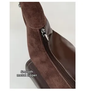 Dettaglio della cerniera in metallo argento e cuciture su borsa in pelle scamosciata marrone