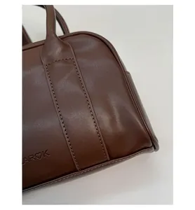 Detail of dark brown leather handbag showing fine stitching and embossed brand logo