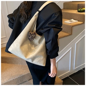 Chic beige tote bag with leopard print charm shown in a cozy staircase scene
