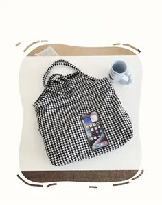 Detail view of houndstooth tote bag size comparison with a smartphone for scale