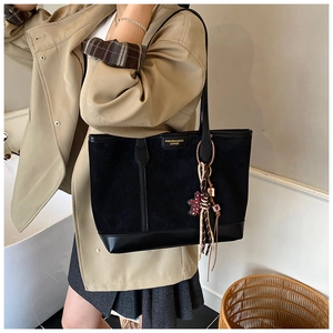 Detail of suede and leather tote bag featuring a leopard bear charm and golden logo