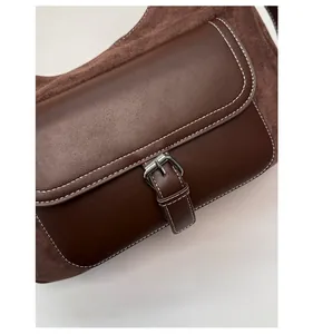 Dettaglio della borsa a tracolla marrone con texture scamosciata e cuciture a contrasto