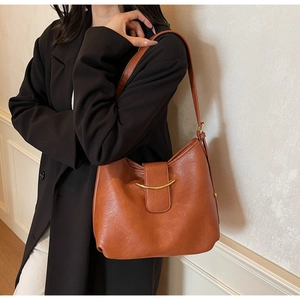 Detail of vintage brown leather hobo bag featuring a crescent gold metal buckle closure