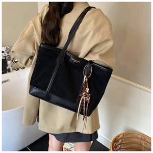 Dettaglio della grande borsa tote nera con mix di trame in pelle e scritte moda dorate