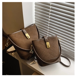 Detail of two brown quilted bucket bags with gold hardware and suede texture