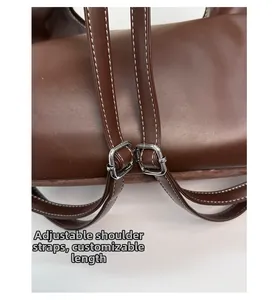Dettaglio tracolla regolabile in pelle marrone con fibbia argentata sulla borsa